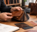 Person holding leather swatches, with leather bags and sketches on a wooden table