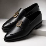 Black leather loafers with gold crest embellishment