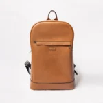 Tan leather backpack with a zippered front pocket and adjustable straps
