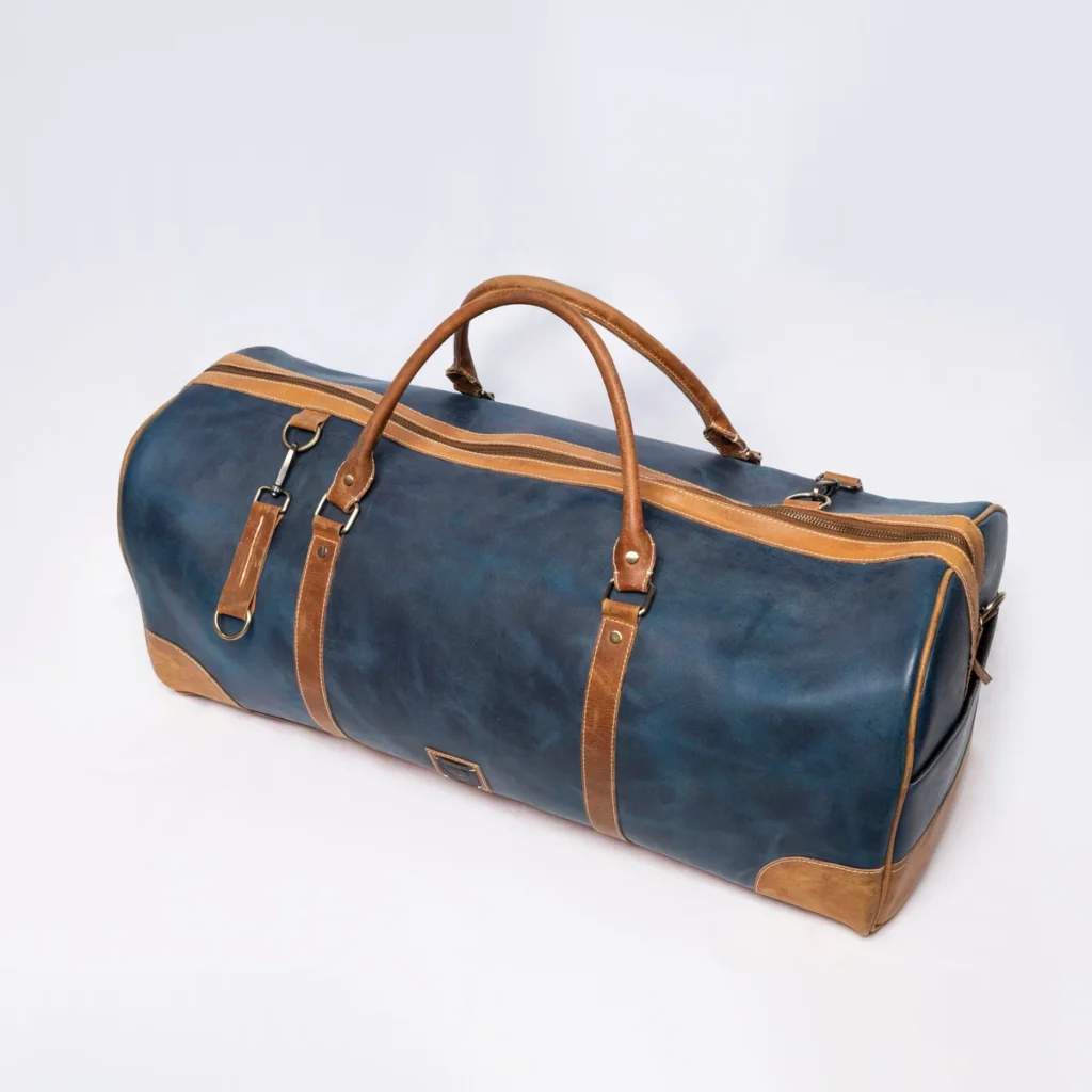 Blue and tan leather duffel bag with double handles and strap accents