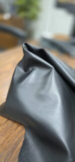 Black leather fabric draped on a wooden surface
