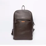 Brown leather backpack with a front zipper pocket and a small orange logo tag