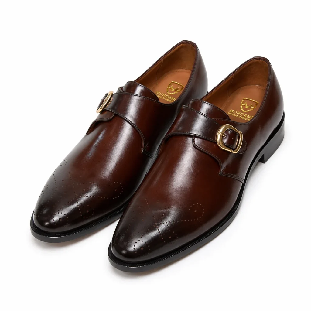Brown leather monk strap shoes with brogue detailing and gold buckles