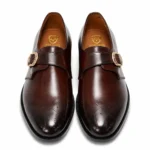 Brown leather monk strap shoes with gold buckle and brogue detailing