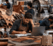 Leather factory workers examine hides and a stressed manager works at a laptop