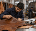 Man inspecting a piece of brown leather with a gauge and color swatches on a table