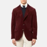 Man wearing a burgundy corduroy blazer over a navy sweater and white shirt, paired with cream trousers